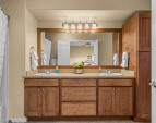 En suite bath featuring dual sinks, wood cabinetry, and shower/tub combo