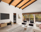 Soaring beamed ceilings create a sense of grandeur, while a dramatic wall of windows floods the space with natural light and offers breathtaking views of the expansive, lush park.