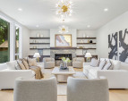 Custom built-in shelves and cabinets, dual chandeliers, and a modern fireplace with TV hookup.