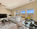 Spacious living room with natural light, picture windows, and open flow to dining and kitchen