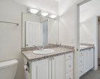 Primary bathroom view showing sink in bathroom and also in vanity area with walk in closet beyond.