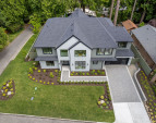 The house perched on a quiet, elevated corner lot surrounded by lush greenery