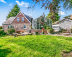 Side yard, greenhouse with stone patio, and storage shed.