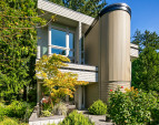 The home is surrounded by lush gardens and enjoys a sunny SW exposure, with two upper balconies and a large patio.