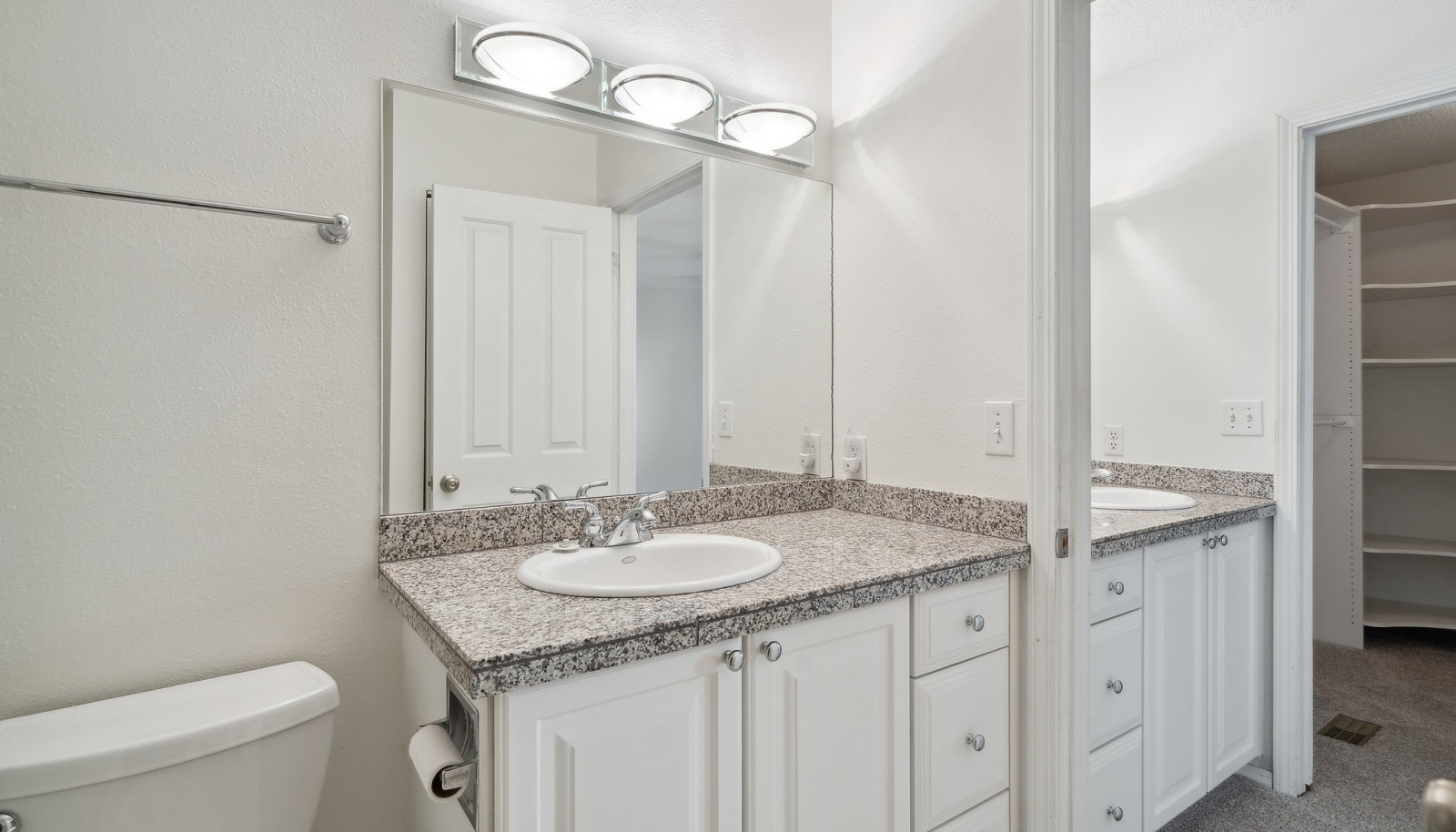 Primary bathroom view showing sink in bathroom and also in vanity area with walk in closet beyond.