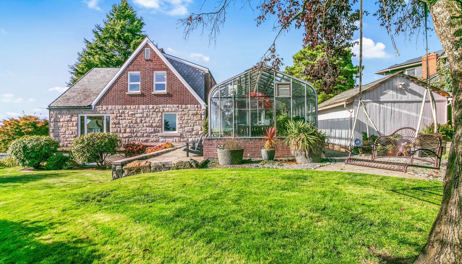 Side yard, greenhouse with stone patio, and storage shed.