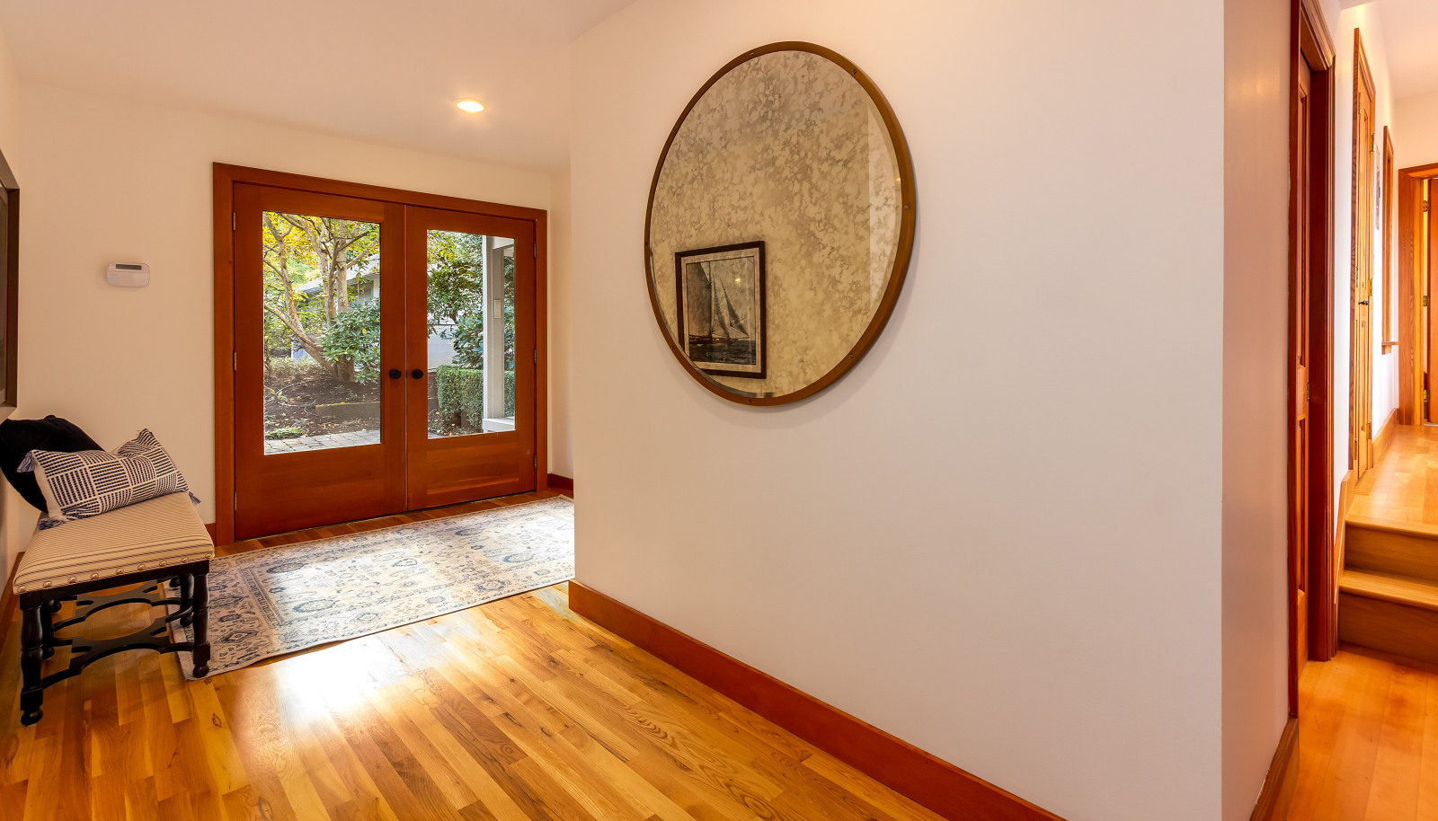 The foyer with French doors and white oak floors. There is a coat closet and powder room upon entry on the left.