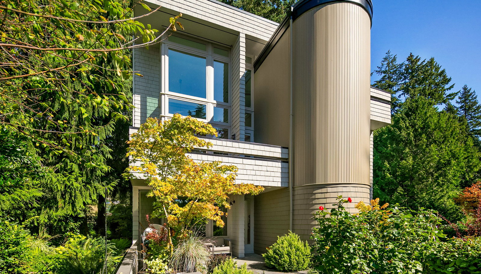The home is surrounded by lush gardens and enjoys a sunny SW exposure, with two upper balconies and a large patio.