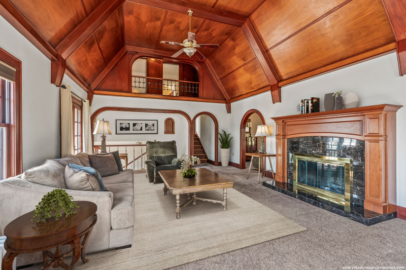 Balcony off the attic looks out on the mahogany vaulted ceilings and cozy wood-burning fireplace. Note partial virtual staging