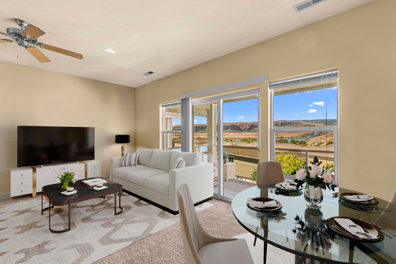 Spacious living room with natural light, picture windows, and open flow to dining and kitchen