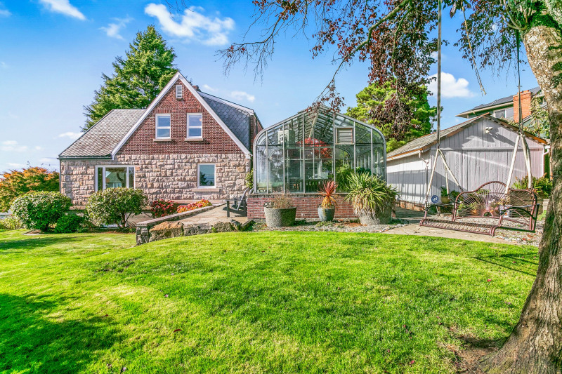 Side yard, greenhouse with stone patio, and storage shed.