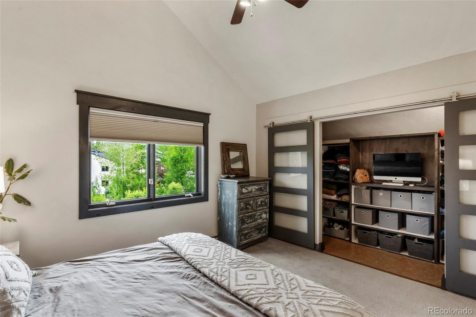 Master bedroom walk in closest with modern sliding glass doors.